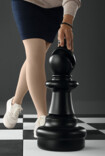 Woman in Juzo Dynamic stockings stands on a large chessboard next to the bishop